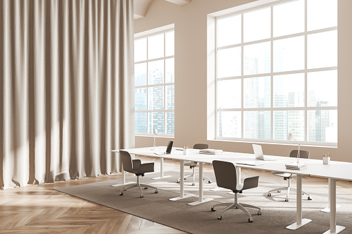 Light meeting interior with chairs and laptop on table, side view, carpet on hardwood floor. Office space with curtain and panoramic window on Singapore skyscrapers. 3D rendering